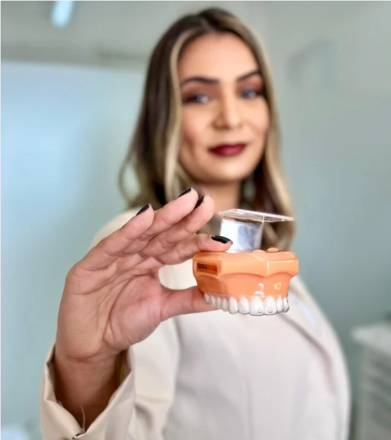 Tatiane - Dentista em Cotia segurando dentadura
